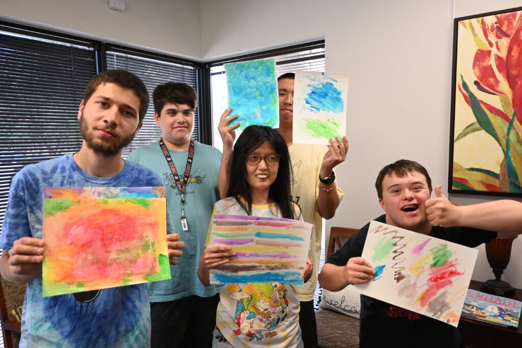 Plano Group holding up watercolor paintings